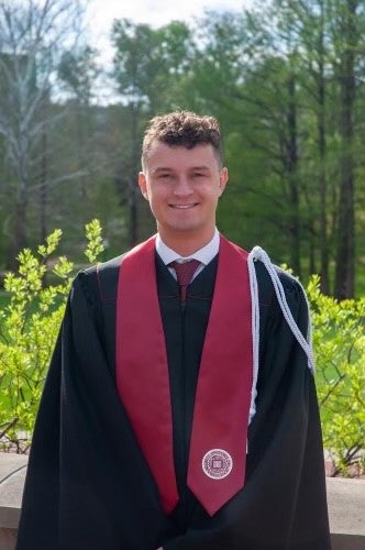 Mason Johnson stands in his cap and gown after graduating form IU Bloomington.