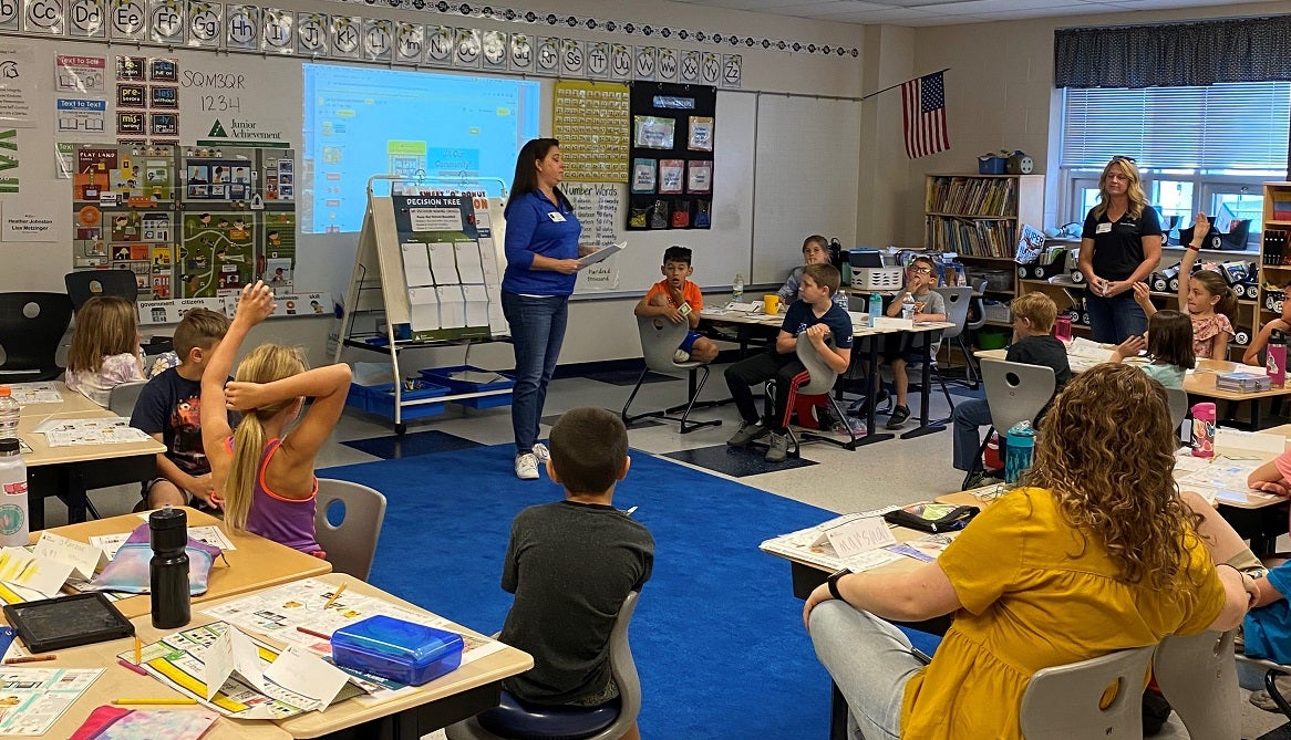 A JA volunteer instructs a classroom of students during a JA program