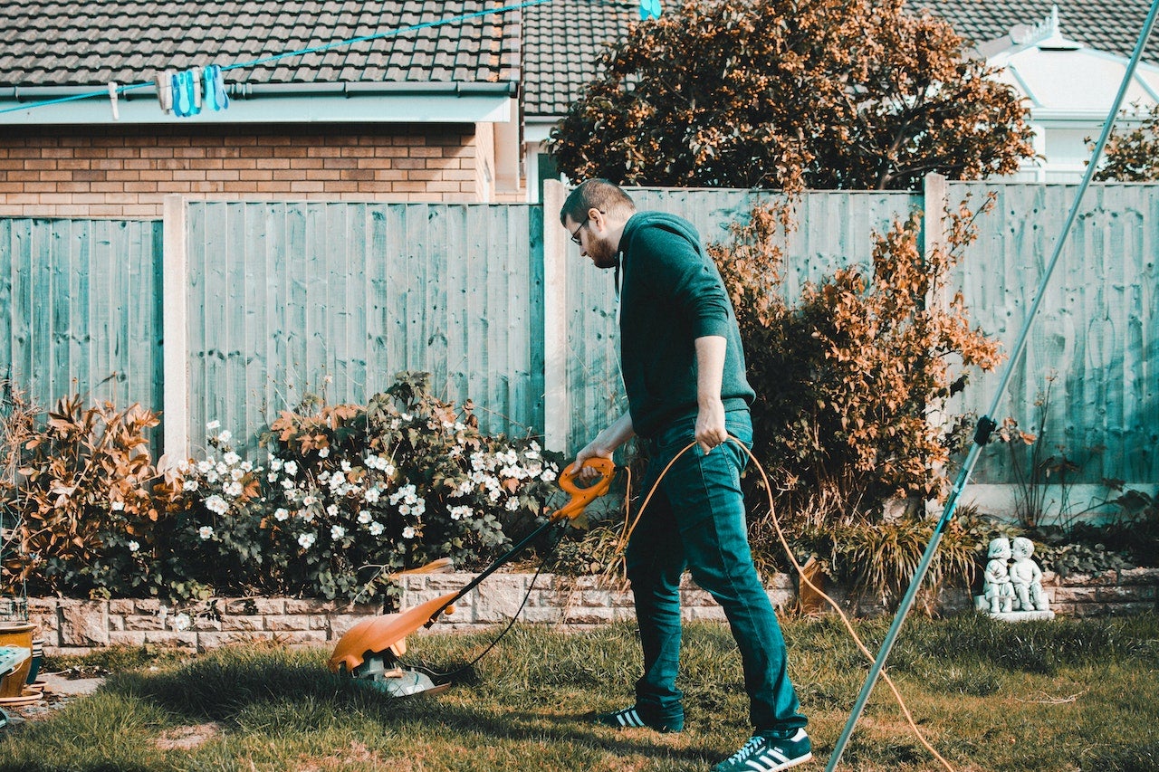 A man trims weeds in his yard